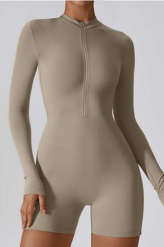 
                  
                    Beige bodysuit with long sleeves and a front zipper on a plain background
                  
                