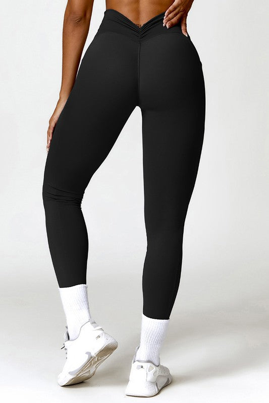 Person wearing black leggings and white sneakers on a plain background