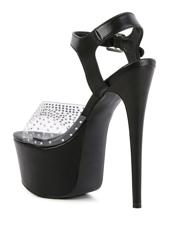 A rear three-quarter view of the black 'First Date' sandal, showcasing the extremely high stiletto heel, the thick black platform sole, and the clear toe strap studded with rhinestones. Available from CO-Wear in Denver, Colorado USA.