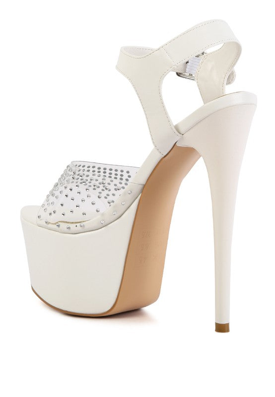 A rear three-quarter angled view of the white 'First Date' sandal, showcasing the ultra-high stiletto heel, the thick white platform sole, and the clear toe strap studded with rhinestones. Available from CO-Wear in Denver, Colorado USA.