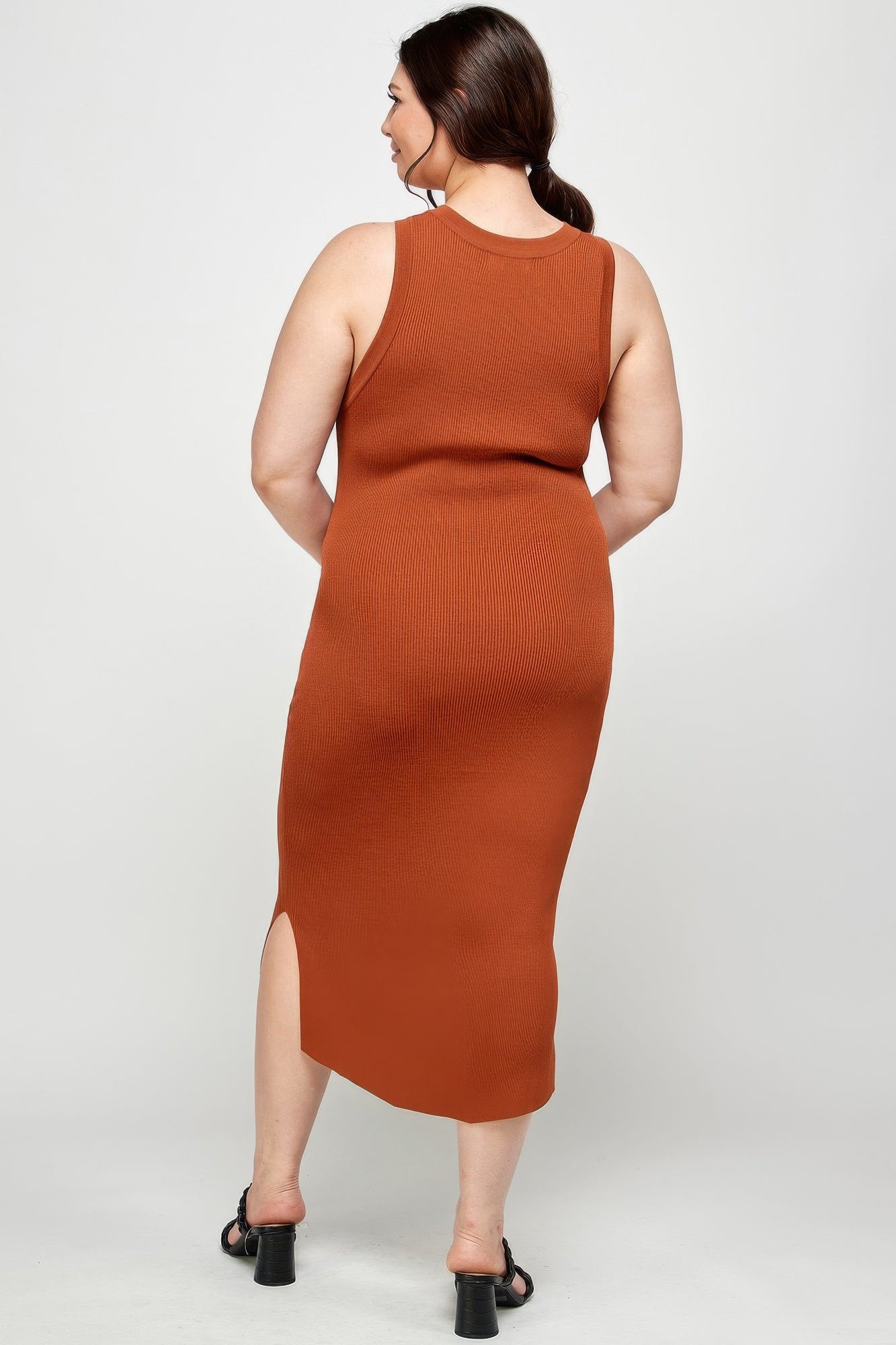 Rear view of a model in a plus size, rust-colored stretchy ribbed knit midi dress, showing the racer back and the fit of the fabric. Denver, Colorado USA.