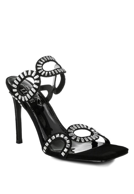 A black suede open-toe stiletto heel sandal featuring straps embellished with circular, rhinestone-lined cut-outs. The shoe has a modern square toe design. Available from CO-Wear in Denver, Colorado USA.