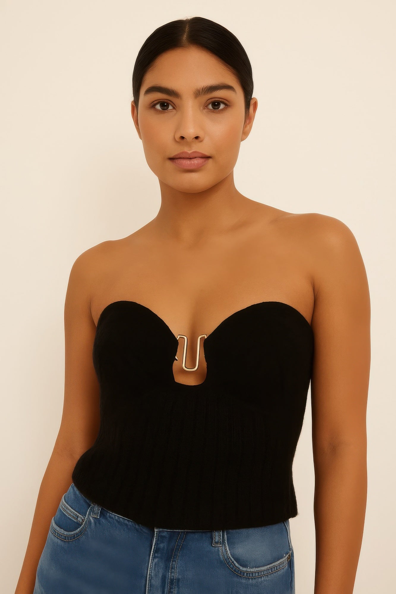 Close-up of a model wearing a black strapless ribbed knit top with a sweetheart neckline and gold metal detail at the bust. Denver, Colorado USA.