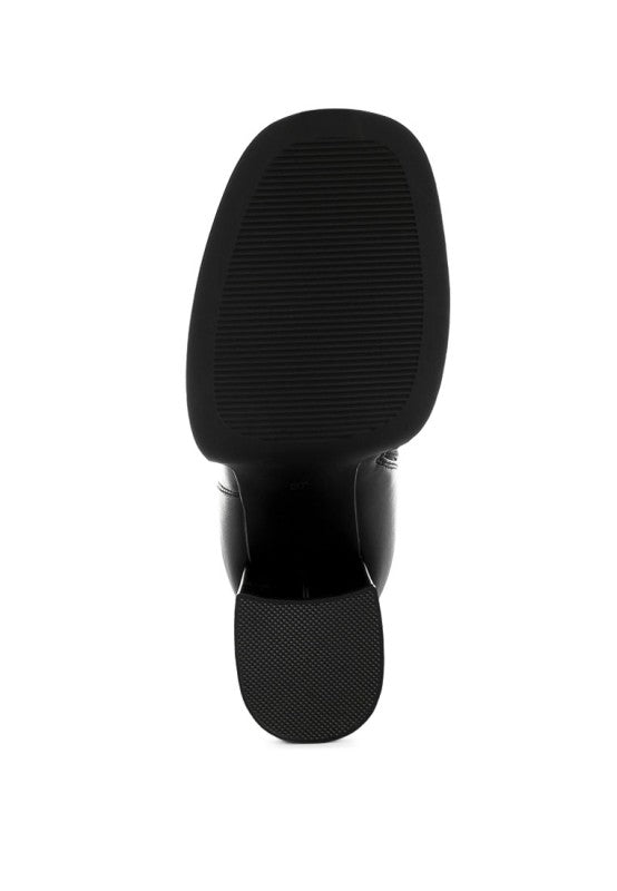 A bottom view of the black leather chunky platform boot, showing the rectangular, thick rubber sole with horizontal grooves and the textured grip patch on the base of the block heel. Available from CO-Wear in Denver, Colorado USA.