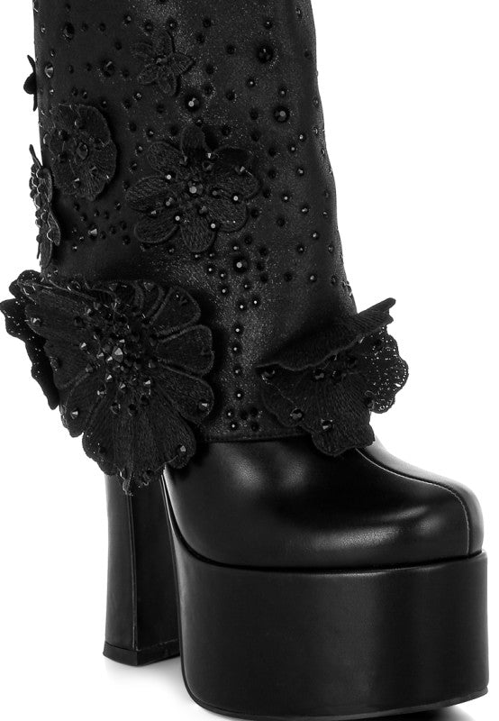 A close-up view of the black 'Sundra' platform boot, focusing on the intricate three-dimensional black floral appliques and tiny bead accents on the shaft just above the massive platform sole. Available from CO-Wear in Denver, Colorado USA.
