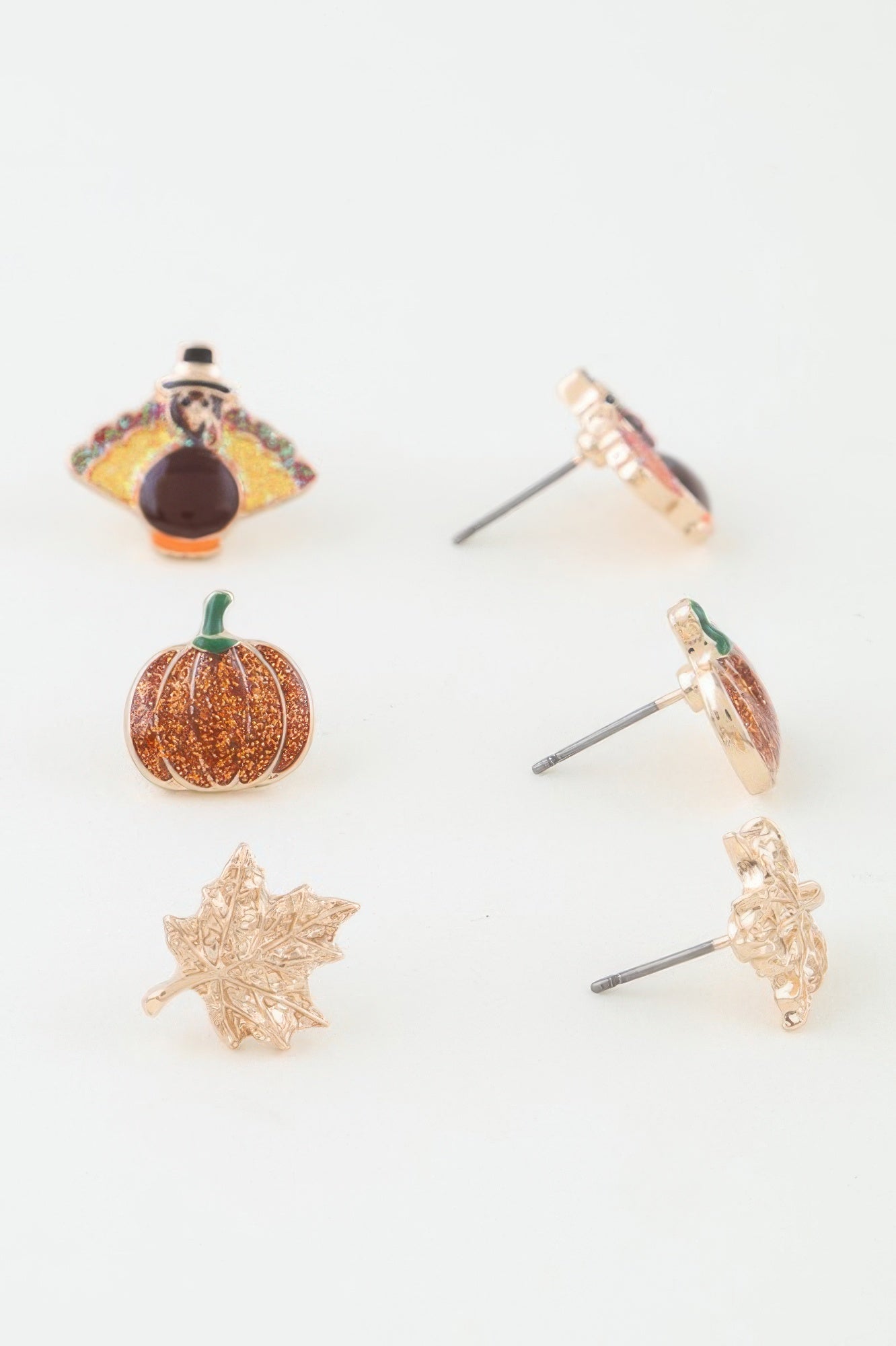 Close-up showing the detail of the turkey, glitter pumpkin, and maple leaf stud earrings, with the posts visible on the back side of the right column. Available from CO-Wear in Denver, Colorado USA.