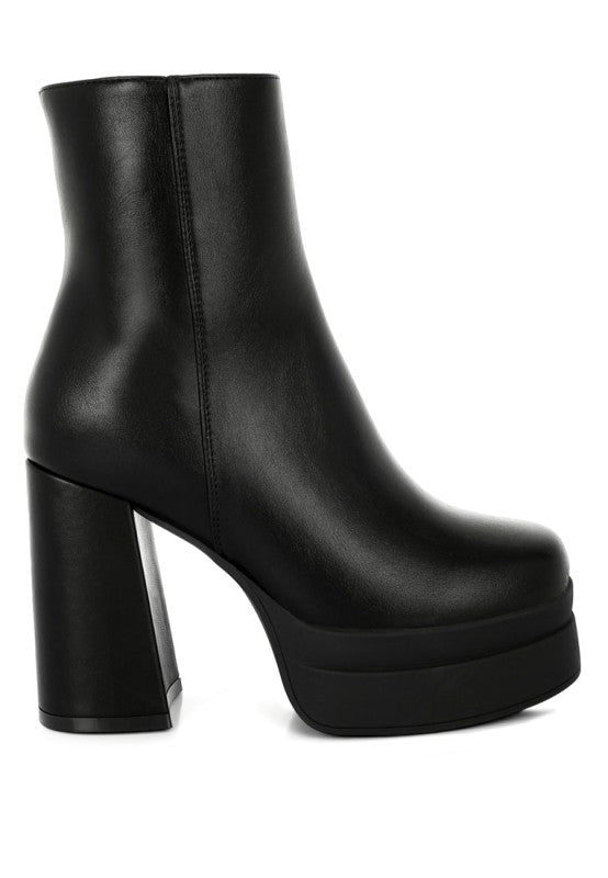 A direct side profile view of the black faux leather chunky platform boot, featuring a thick, layered platform sole and a massive, angled block heel for a high-fashion look. Available from CO-Wear in Denver, Colorado USA.