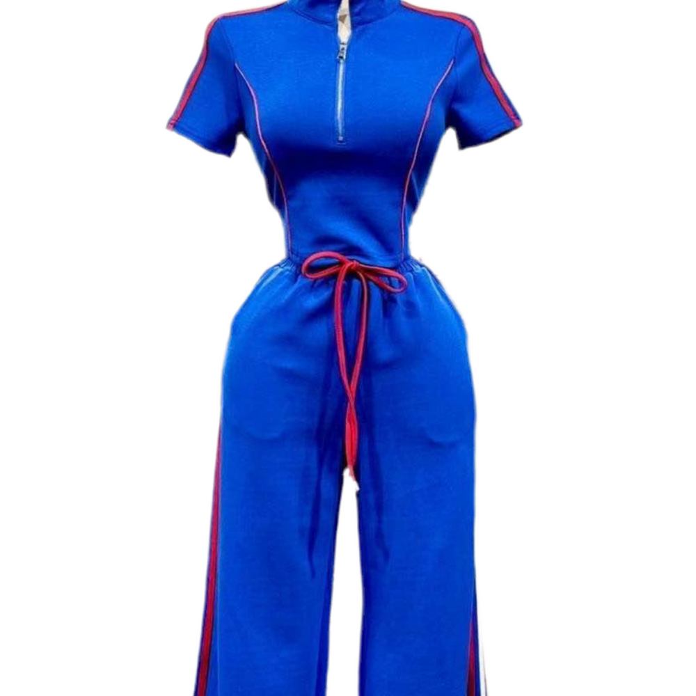 A vibrant blue jumpsuit with short sleeves and a high collar is displayed. It features a half-zip front, red piping details along the arms and sides of the legs, and a red drawstring at the waist. The pants have a wide-leg silhouette. The background is white.