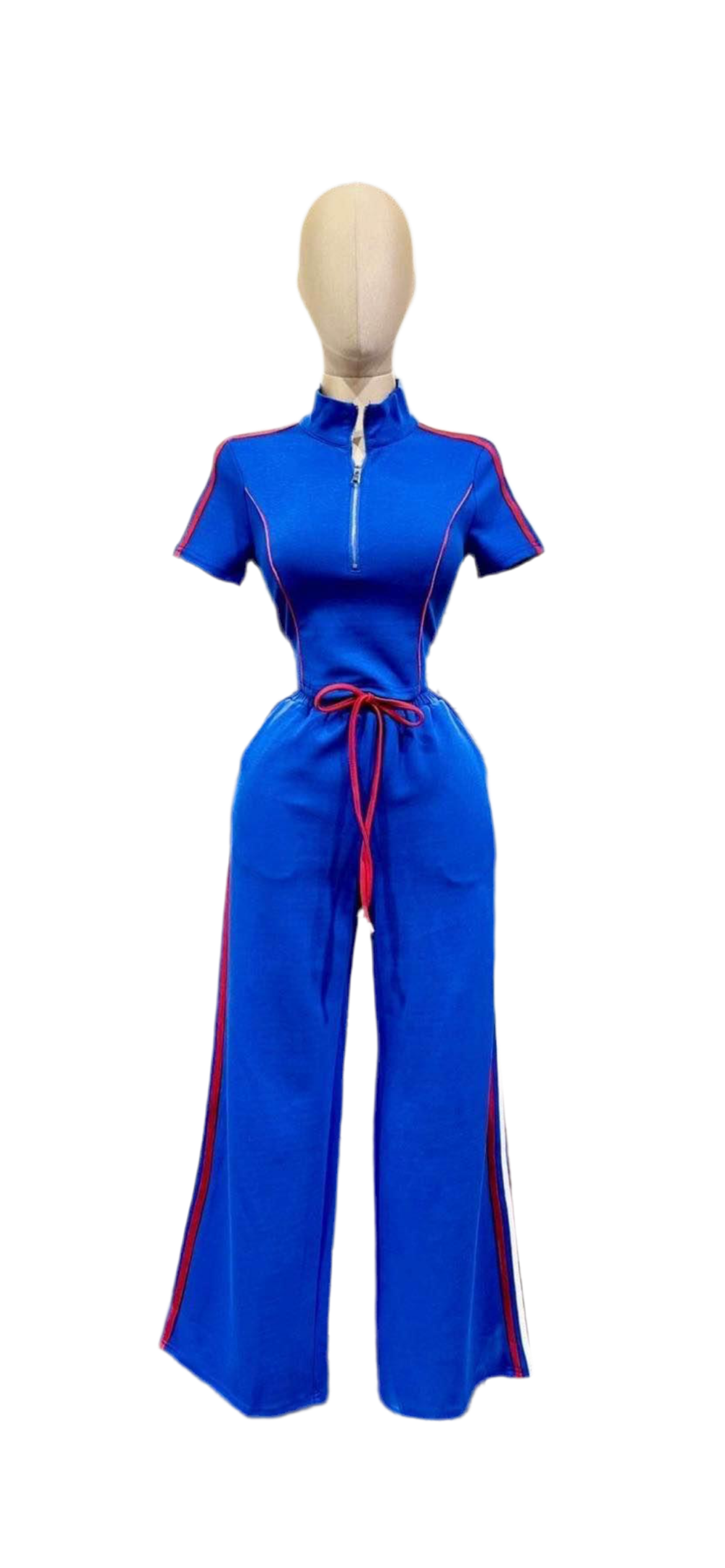 A vibrant blue jumpsuit with short sleeves and a high collar is displayed. It features a half-zip front, red piping details along the arms and sides of the legs, and a red drawstring at the waist. The pants have a wide-leg silhouette. The background is white.