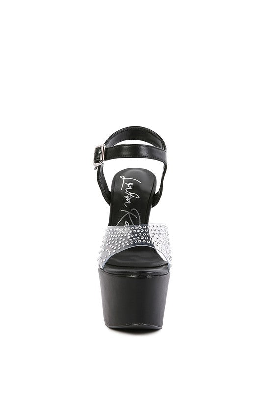 A direct front view of the black 'First Date' sandal, highlighting the massive black platform and the wide, clear toe strap encrusted with rows of rhinestones. Available from CO-Wear in Denver, Colorado USA.