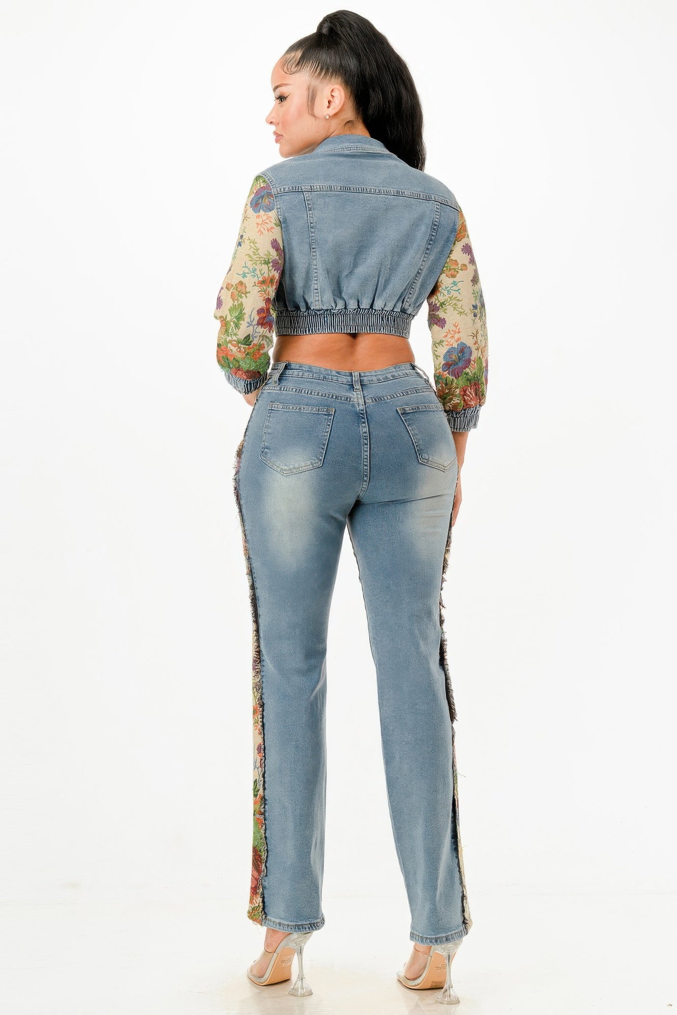Full back view of a model wearing the matching cropped denim jacket and distressed jeans, highlighting the floral tapestry sleeves and side panels. Available from CO-Wear in Denver, Colorado USA.