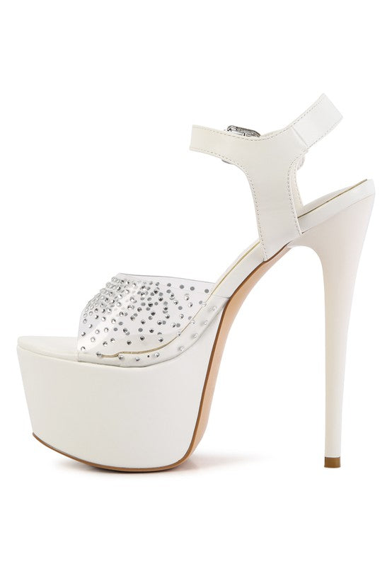 A full side profile view of the white 'First Date' sandal, showcasing the ultra-high stiletto heel, the massive white platform, and the clear toe strap richly studded with rhinestones. Available from CO-Wear in Denver, Colorado USA.