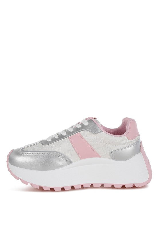 A side profile view of the chunky sneaker, emphasizing the white platform sole with pink trim, the metallic silver toe/heel, and the pink stripe detail across the patterned upper. Available from CO-Wear in Denver, Colorado USA.