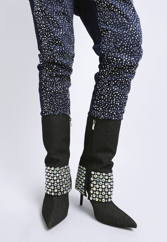 A front view of a model's legs wearing black denim stiletto boots, styled with the cuff folded down to expose rows of iridescent diamante studs. The model is also wearing dark pants heavily embellished with small silver studs. Available from CO-Wear in Denver, Colorado USA.