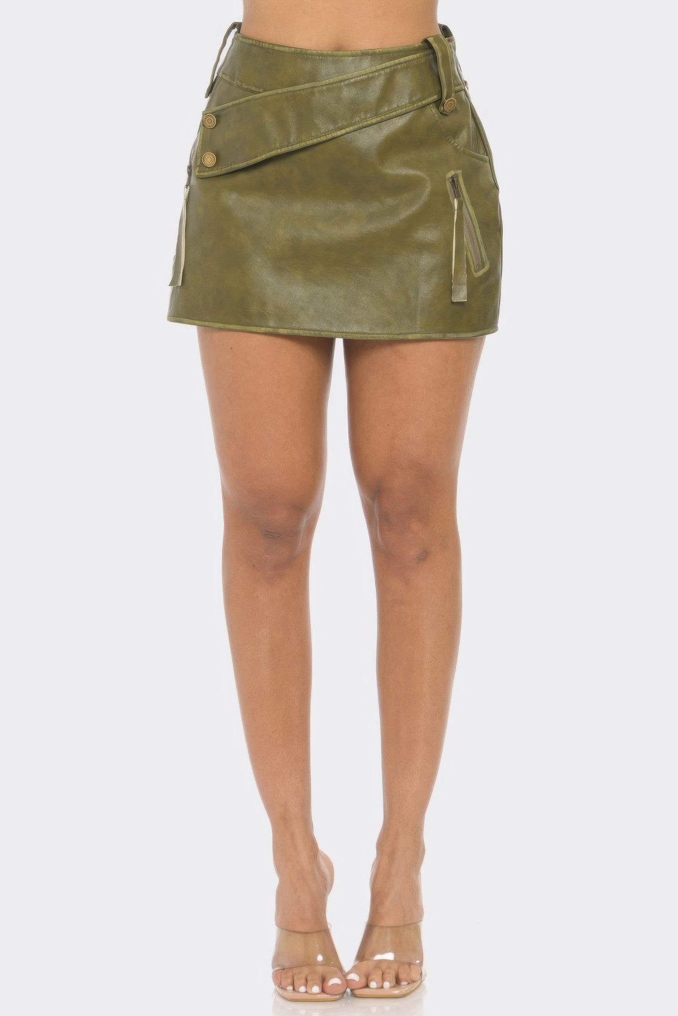 Model standing and wearing an olive green faux mini leather skirt featuring multiple button and zipper details on the front. Denver, Colorado USA.