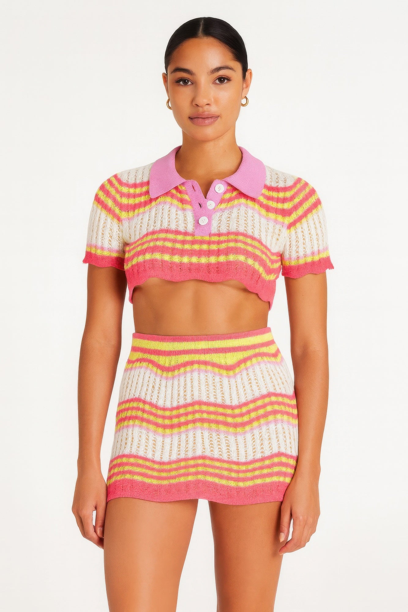 Model wearing a brightly colored Zig Zag Crochet Two Piece Set with a cropped polo top and mini skirt in pink, yellow, and white horizontal stripes. Denver, Colorado USA.