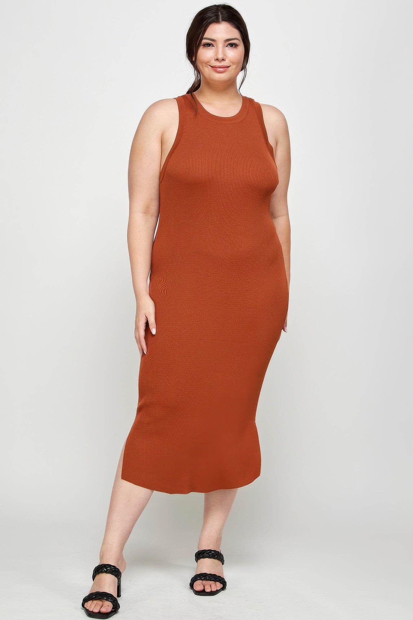 Model in a plus size, sleeveless, rust-colored ribbed knit midi dress with a racer back, minimal side slit, and block heels. Denver, Colorado USA.