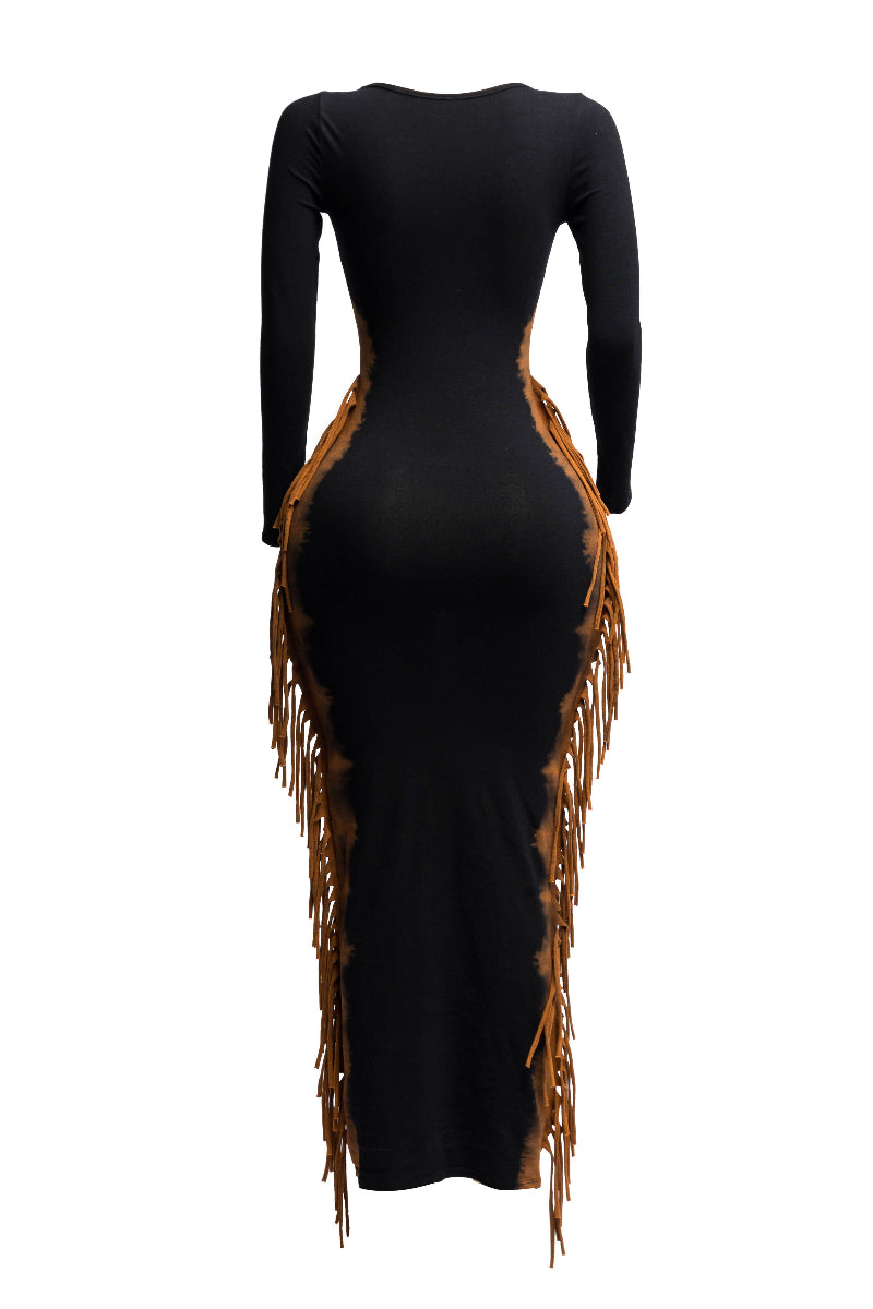 The back view of a black, long-sleeved bodycon maxi dress is displayed on a mannequin. The dress features multiple layers of light brown or tan fringe cascading down both sides from the shoulders to the hem. The top of the dress has a square neckline.