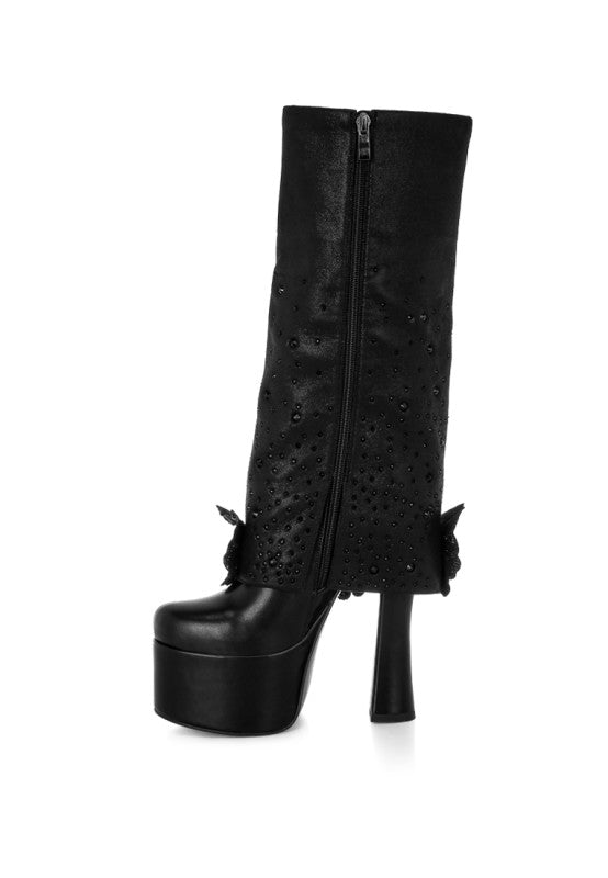 A side profile view of the black 'Sundra' platform boot, showing the full height of the shaft, the side zipper closure, the chunky block heel, and the black floral applique details. Available from CO-Wear in Denver, Colorado USA.