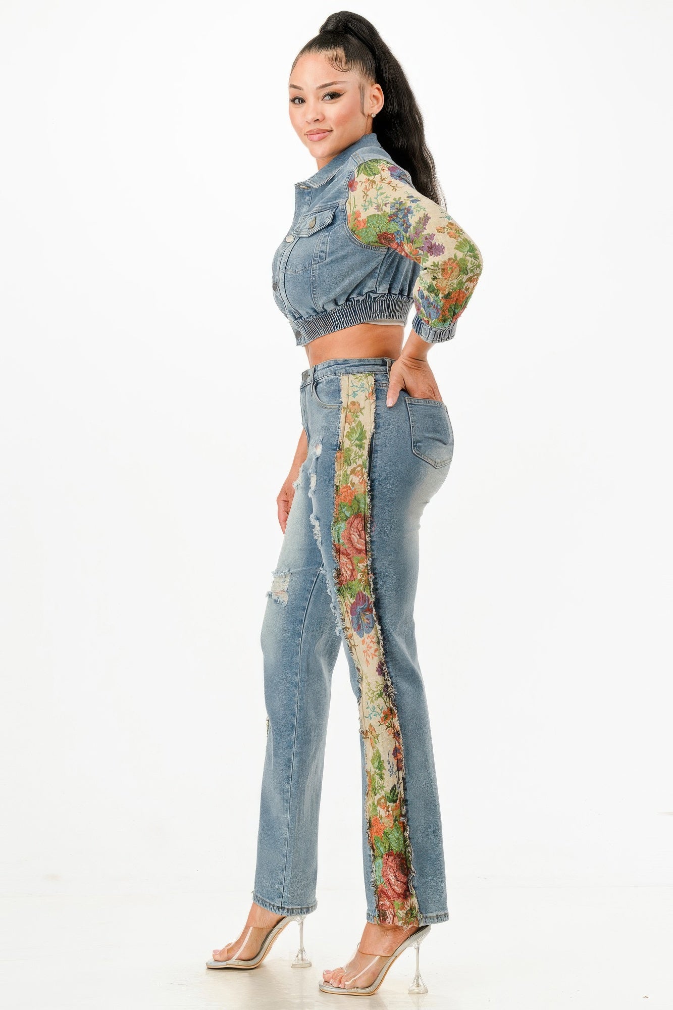 Side-profile view of a model wearing the distressed denim set, highlighting the long floral tapestry panels running down the side seams of the jeans. Available from CO-Wear in Denver, Colorado USA.