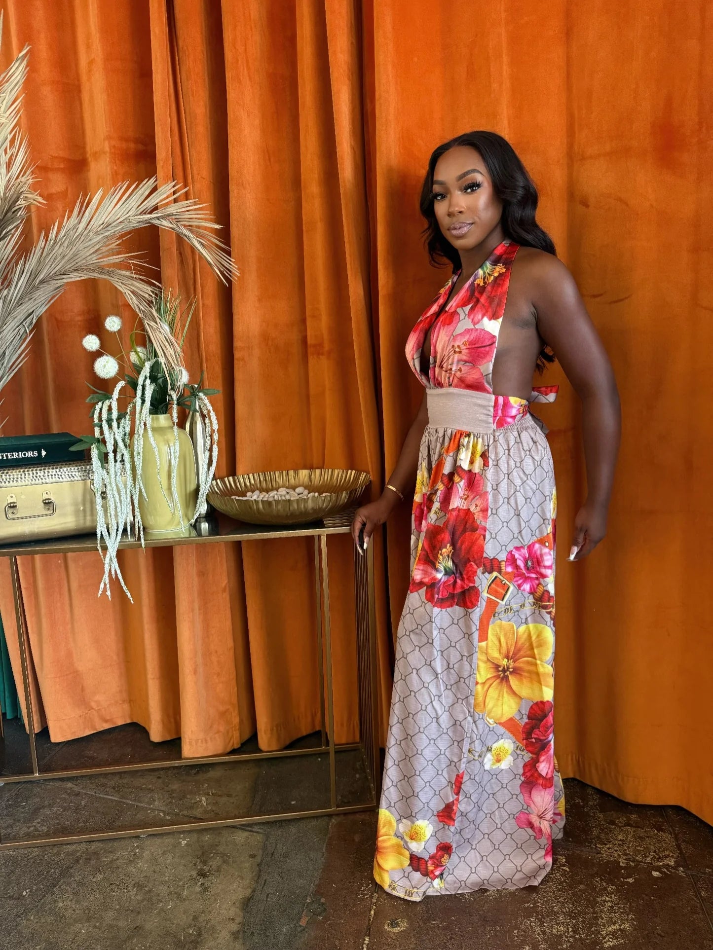 Side view of the model in the Paradise Bloom Jumpsuit, showing the open sides and vibrant floral print against an orange backdrop. Denver, Colorado USA.