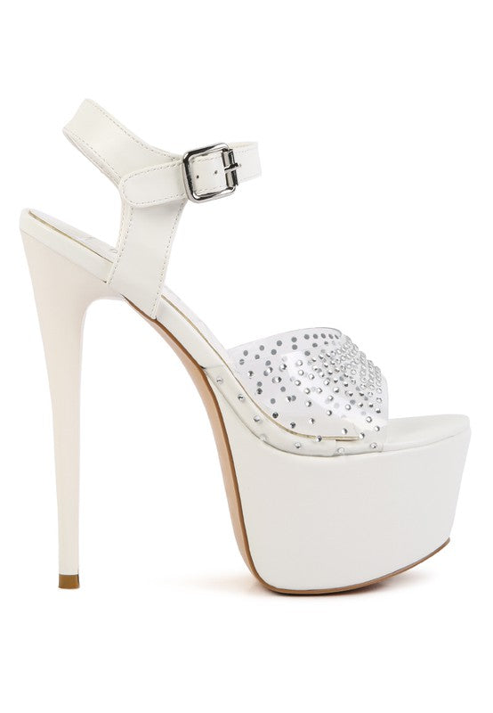 A side profile view of the white 'First Date' sandal, featuring an ultra-high stiletto heel, a thick platform sole, and a clear toe strap heavily studded with small rhinestones. Available from CO-Wear in Denver, Colorado USA.