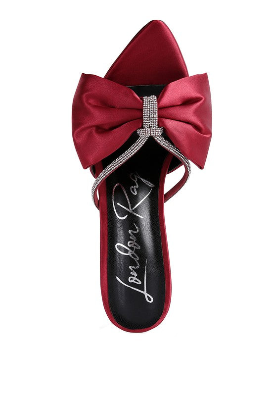 A top-down view of the rich red satin high-heeled sandal, featuring a puffy bow secured with a silver rhinestone band and thin jewel straps across the footbed. The footbed has silver cursive writing. Available from CO-Wear in Denver, Colorado USA.