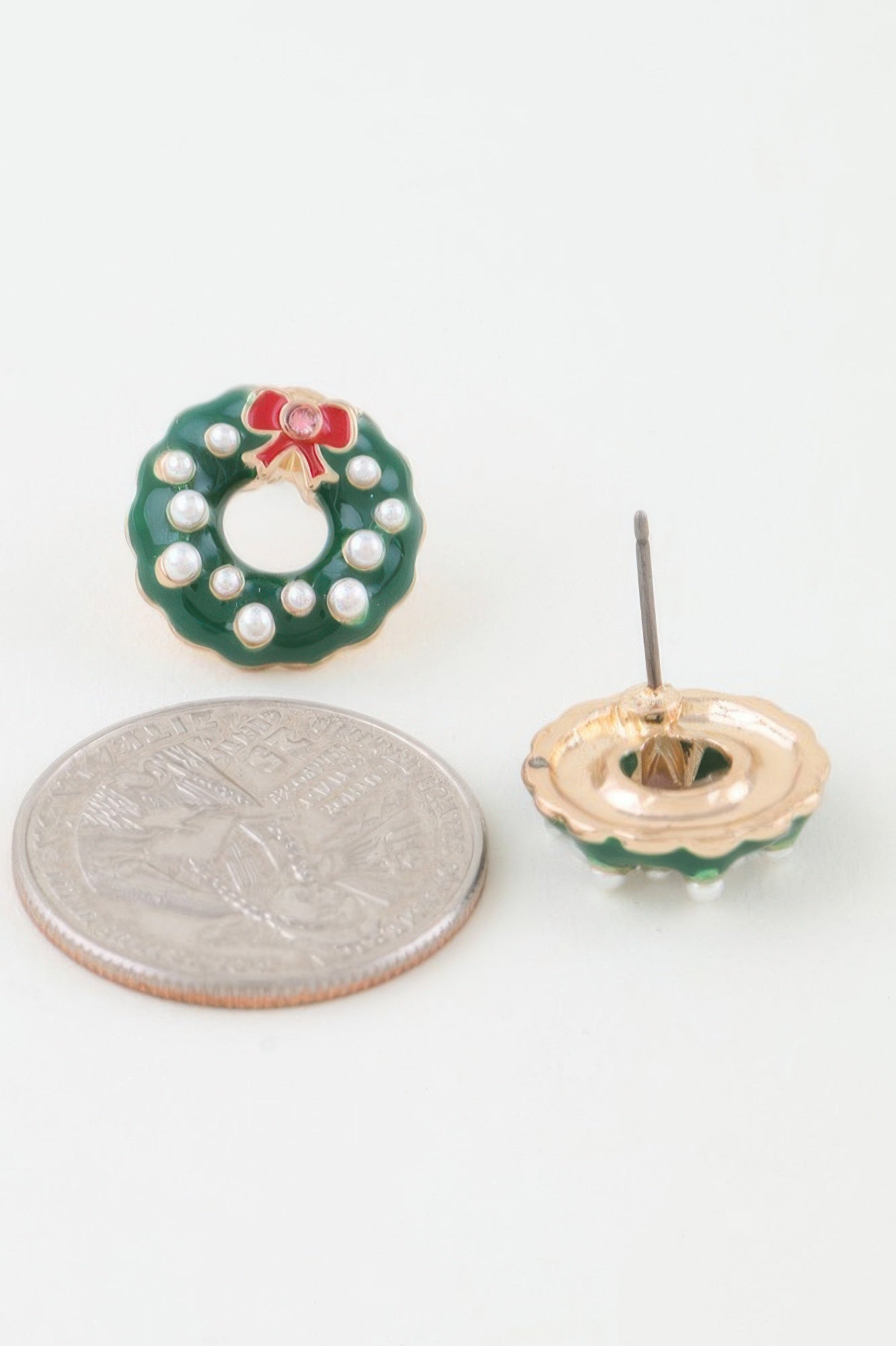 Close-up showing the size of the green enamel wreath stud earring next to a US quarter, with a second earring showing the back post closure. Available from CO-Wear in Denver, Colorado USA.