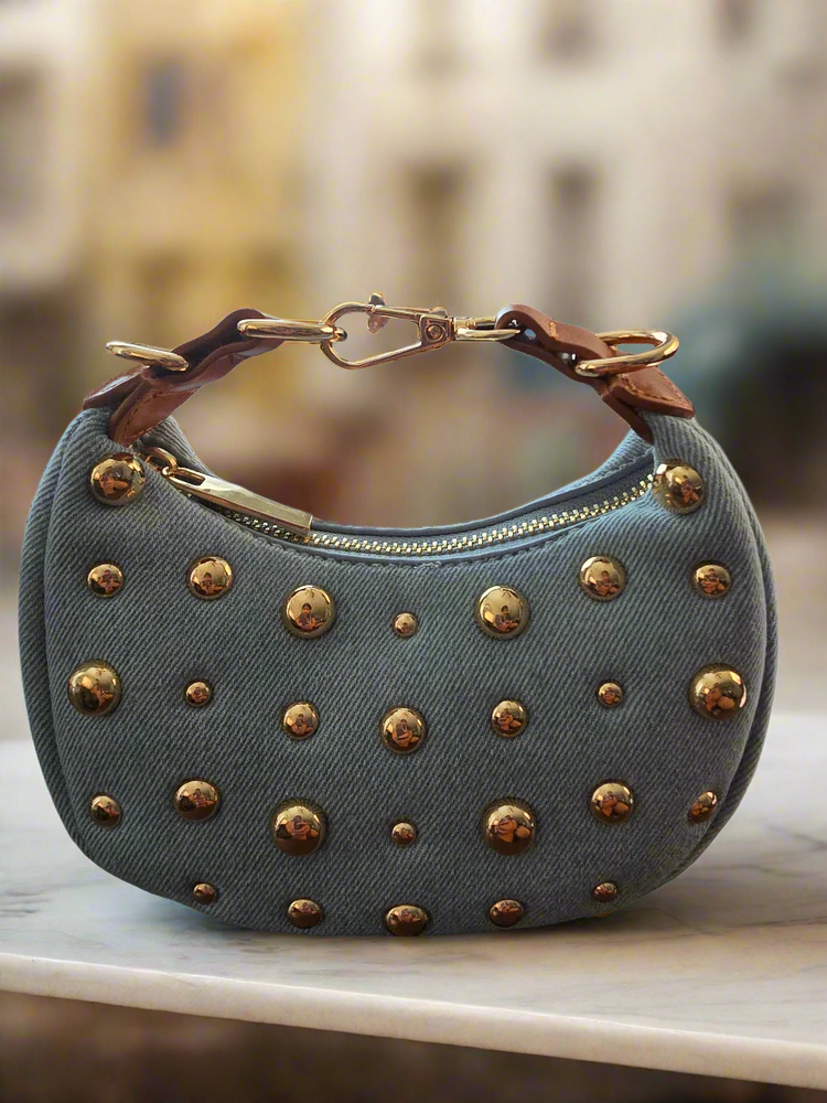 Blue denim handbag with gold studs on a white background