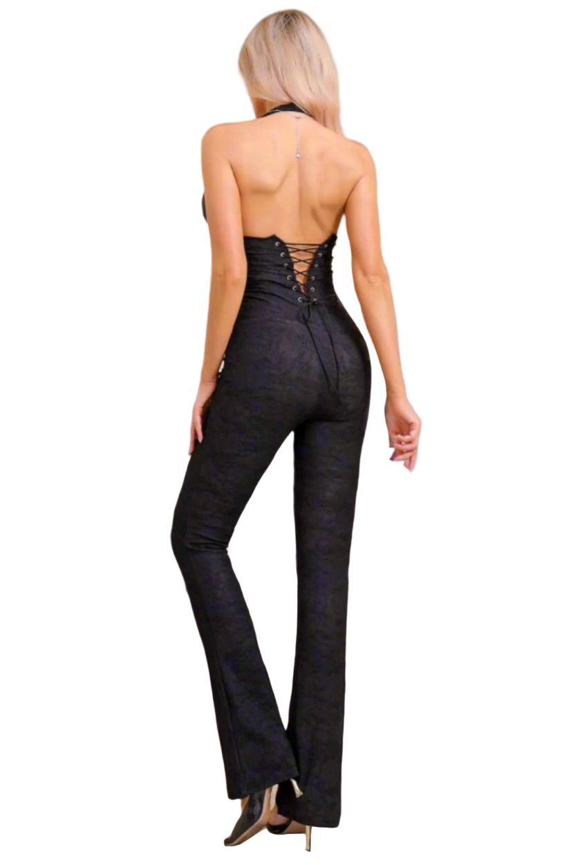 Woman wearing a black jumpsuit with lace-up back in a room setting.
