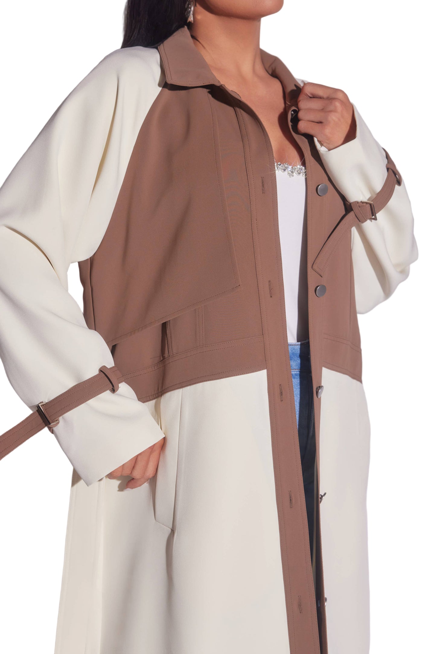 Person wearing a brown and white trench coat with a plain background