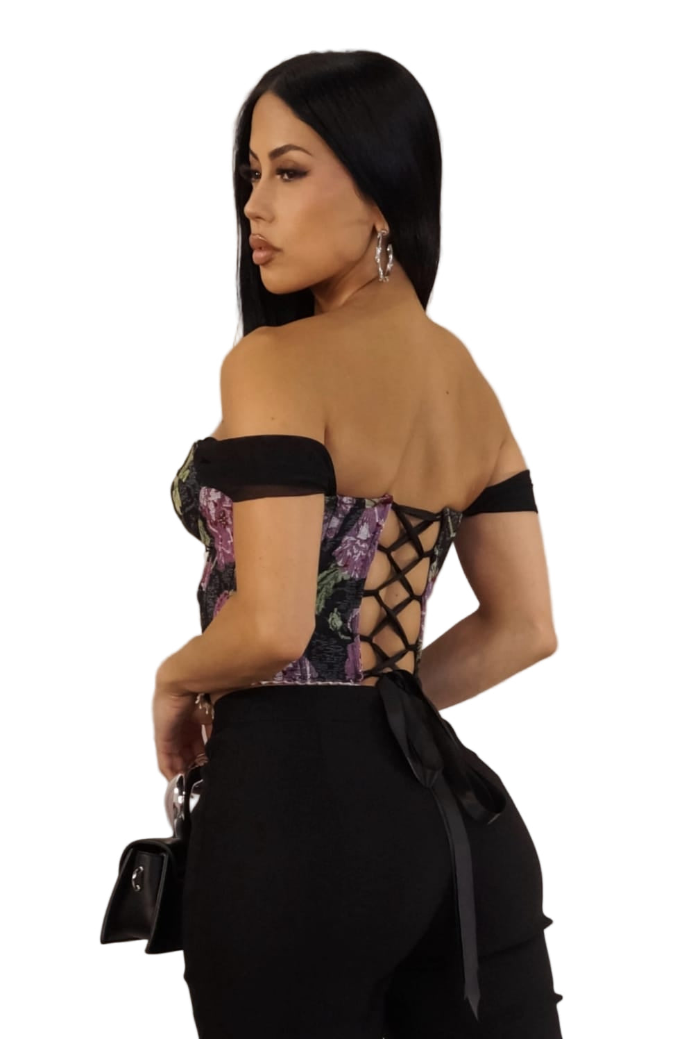 Woman wearing a stylish outfit with floral top and black skirt against a plain background