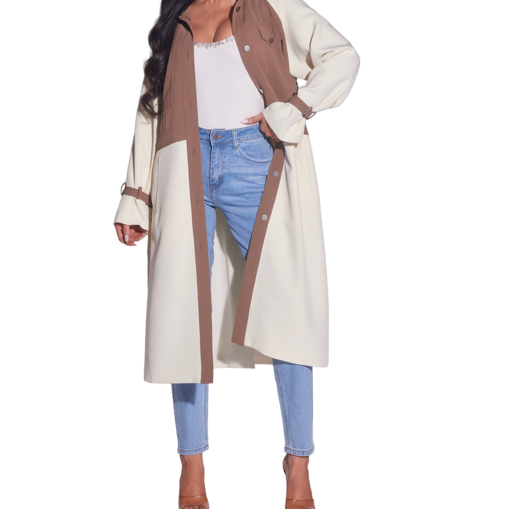 Woman wearing a long beige coat with brown accents on a plain background