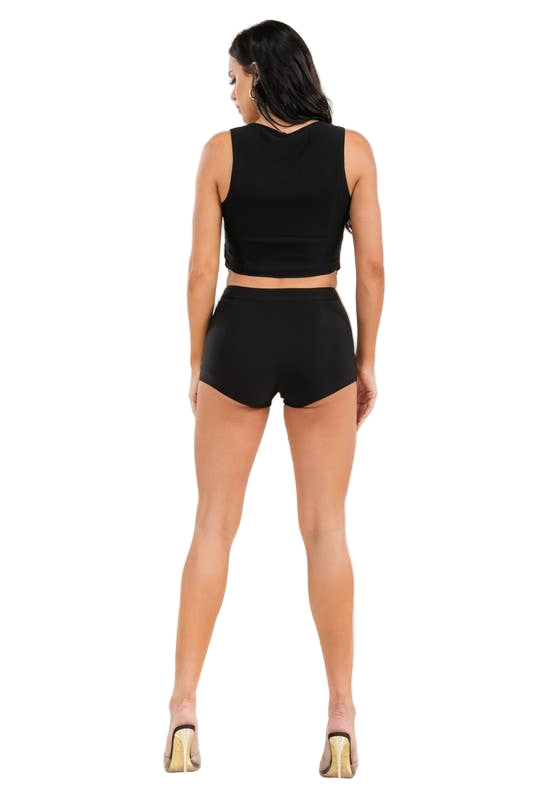 Woman wearing a black sleeveless top and shorts on a beige background